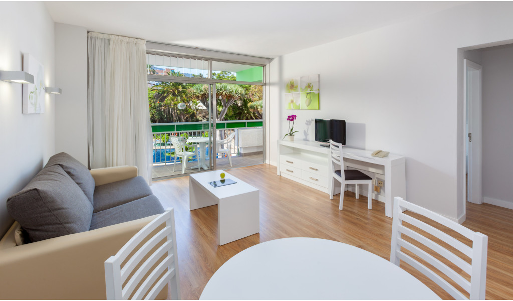 Wohnzimmer mit Sofa, Tisch, Stühlen und Balkon in einer Ferienwohnung in Puerto de la Cruz.