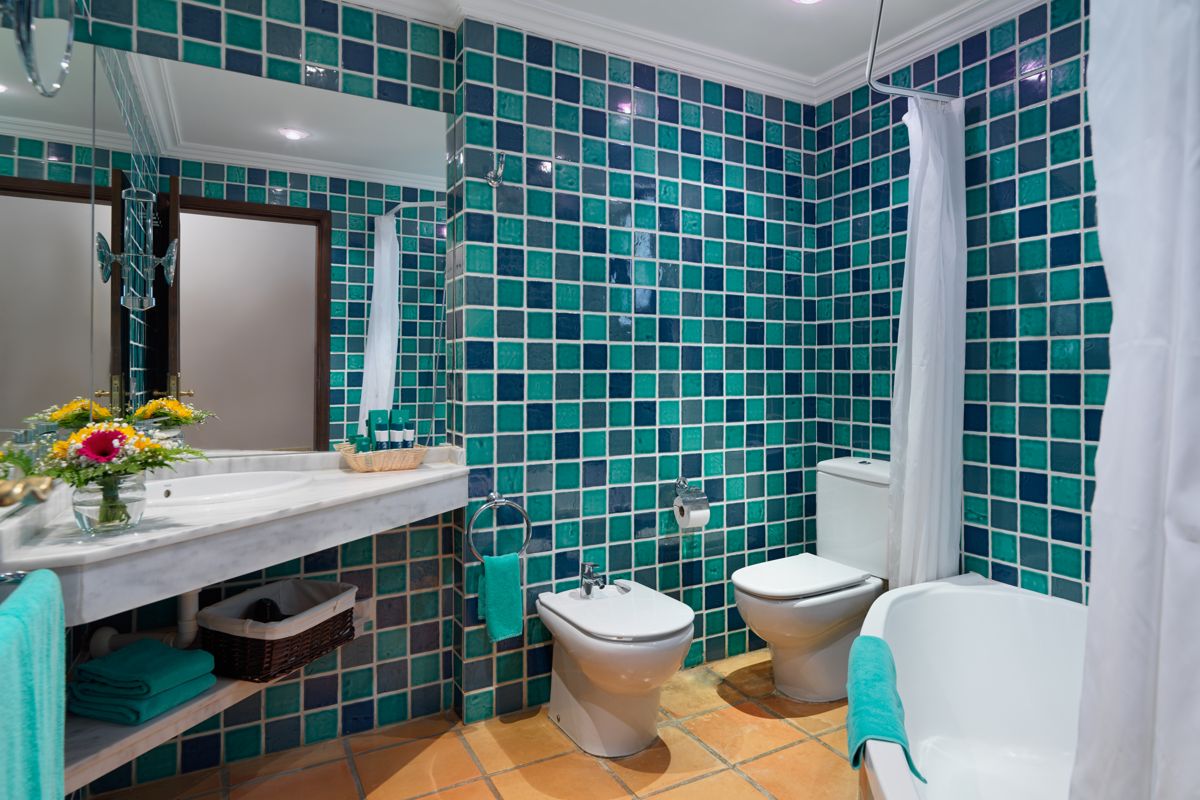 Badezimmer mit blauen Fliesen, Waschbecken, Toilette und Blumen in Puerto de la Cruz.