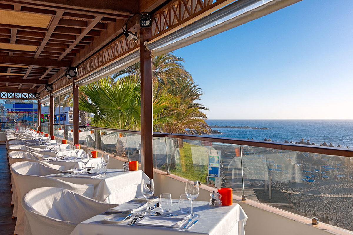Meerblickterrasse in einem Restaurant in Tenerife mit gedeckten Tischen.