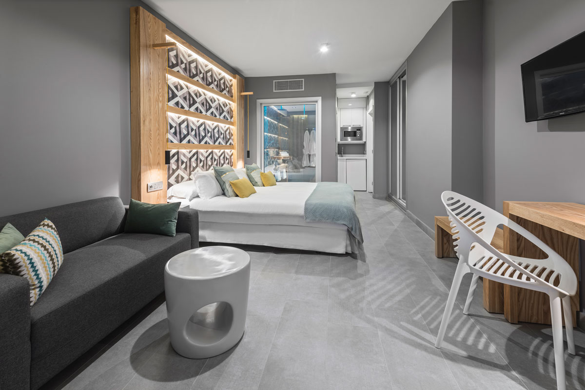 Modernes Hotelzimmer in Santa Cruz de Tenerife mit Bett, Sofa und Küchenzeile.