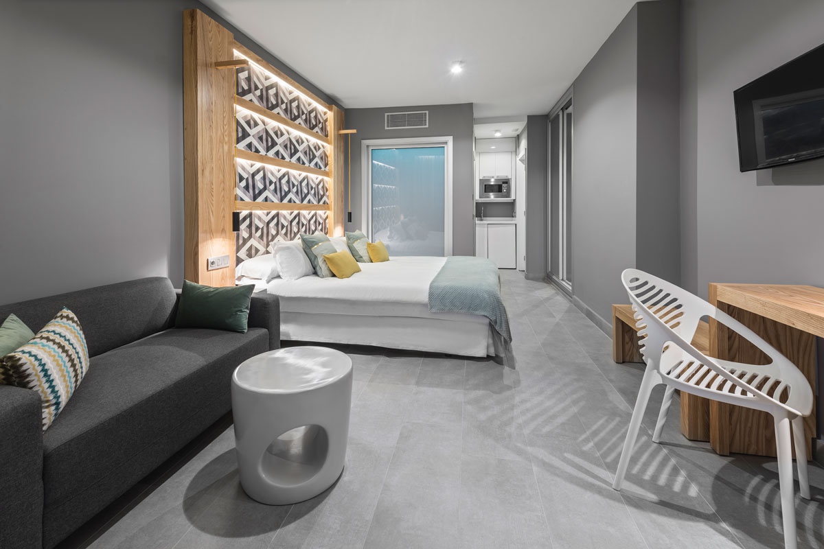 Modernes Hotelzimmer in Tenerife mit Doppelbett, Sofa und kleinen Küche.
