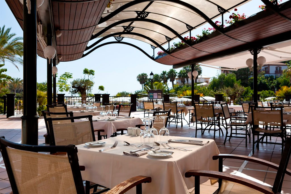 Überdachte Terrassenrestaurant in Tenerife mit gedeckten Tischen und Gartenblick.