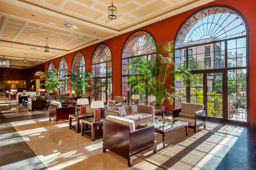 Innenraum eines eleganten Hotels in Tenerife mit großen Fenstern und Sitzbereich.