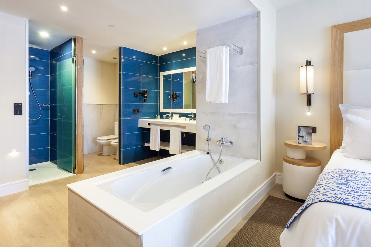 Badezimmer mit blauer Kacheldusche, Waschbecken und Badewanne in Teneriffa.