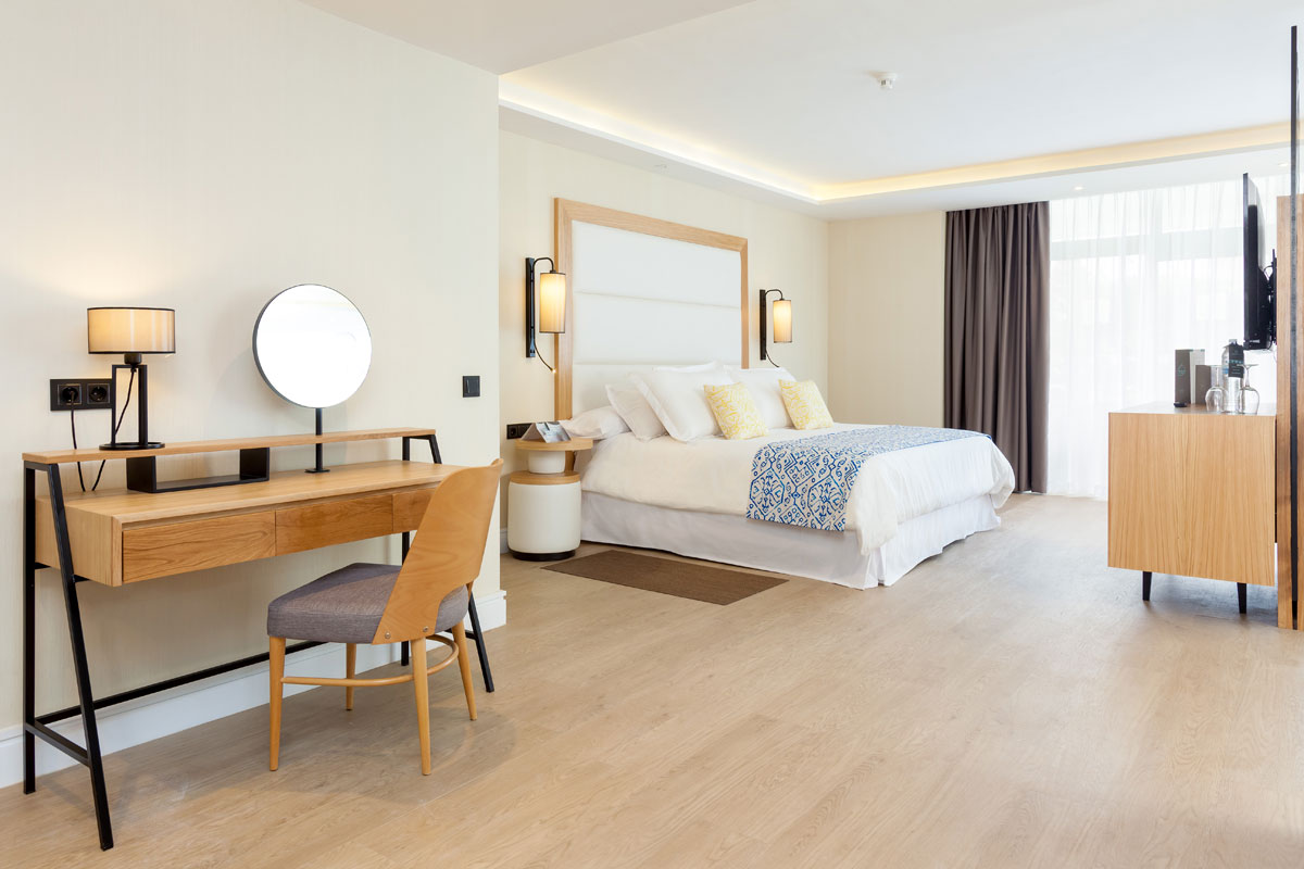 Hotelzimmer in Teneriffa mit Bett, Schreibtisch und Lampe.