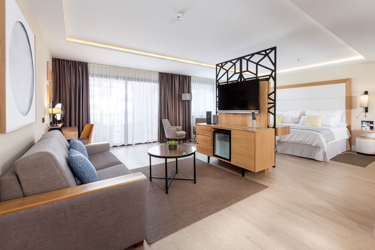 Modernes Hotelzimmer in Tenerife mit Couch, Fernseher und Bett.