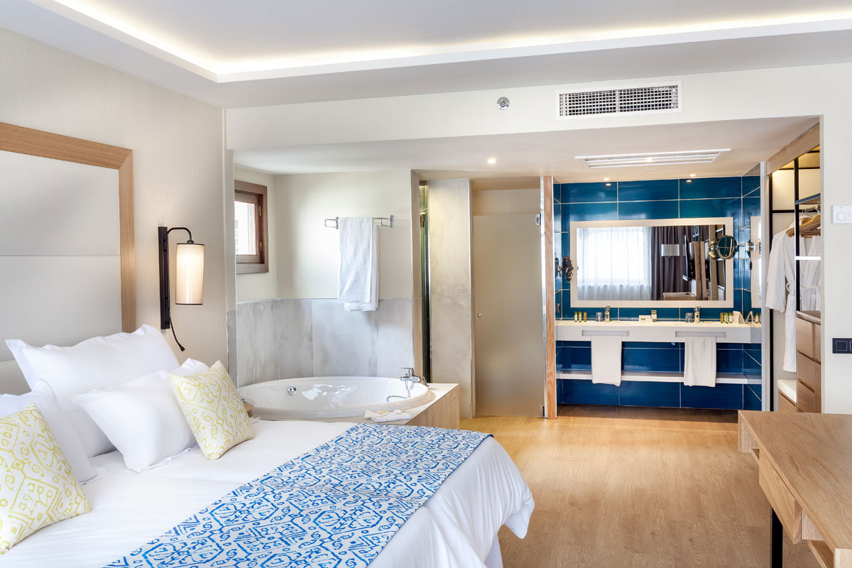 Luxuriöses Hotelzimmer in Teneriffa mit Doppelbett, Badewanne und moderner Einrichtung.