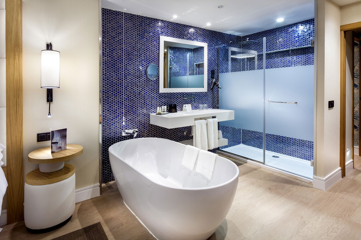 Freistehende Badewanne und Waschbecken mit blauen Kacheln im Hotelzimmer in Tenerife.