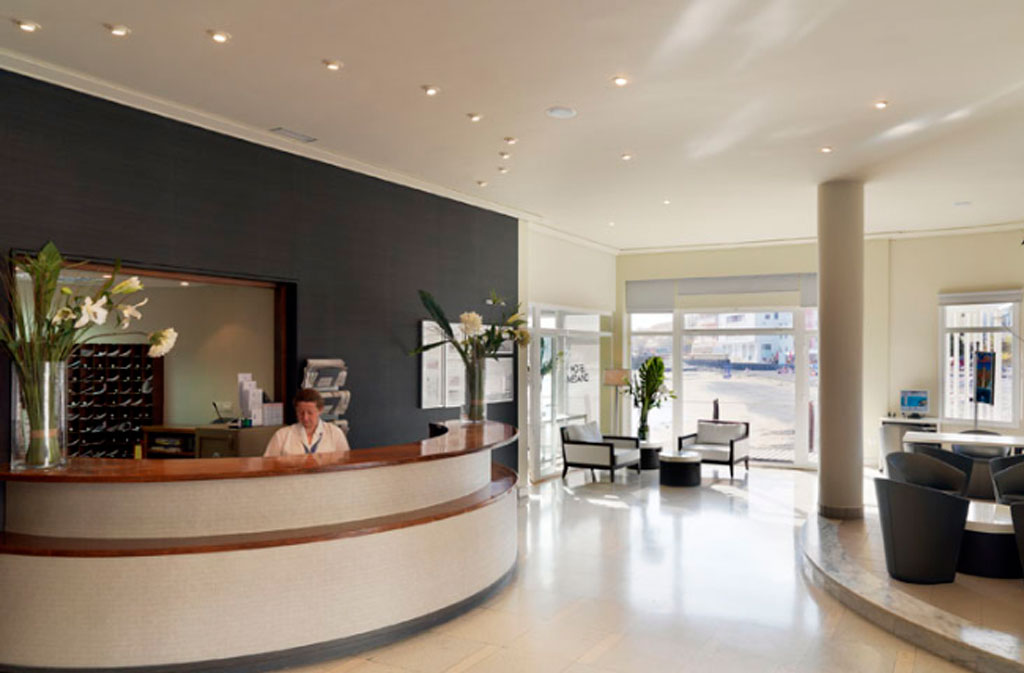 Empfangsbereich eines Hotels in Tenerife mit Sitzbereich und Rezeptionistin.