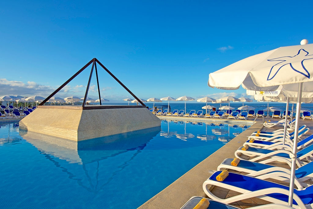 Poolbereich mit blauen Liegestühlen und Sonnenschirmen in einem Hotel in Tenerife.