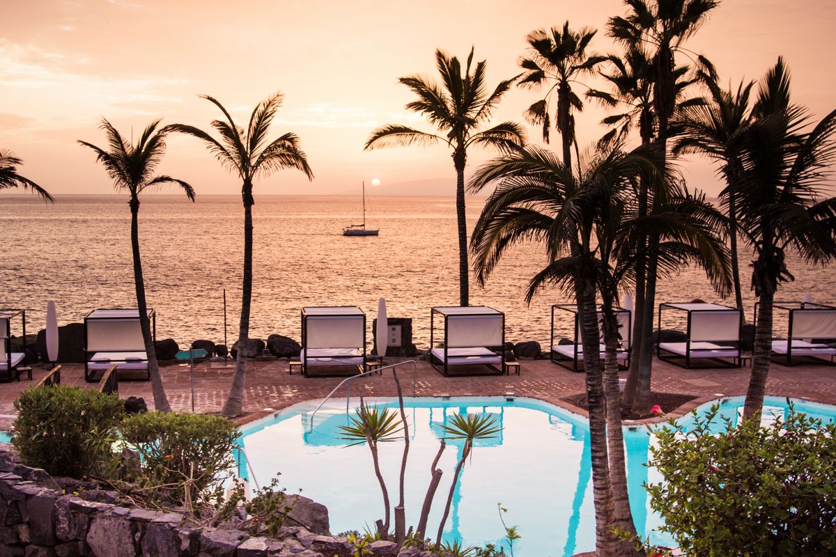 Pool mit Palmen und Sonnenuntergang am Meer in Costa Adeje, Tenerife.