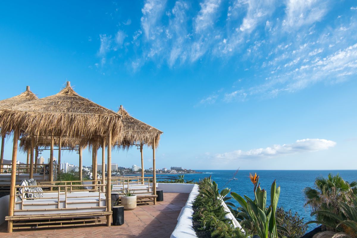 Palmenhütten mit Blick auf das Meer in Adeje, Teneriffa. Himmel und Küste im Hintergrund.
