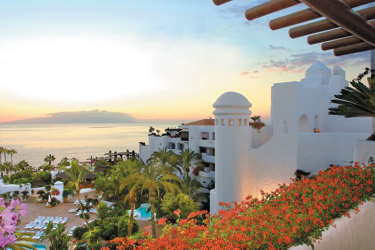 Weißes Gebäude mit Palmen und Meerblick bei Sonnenuntergang in Tenerife.