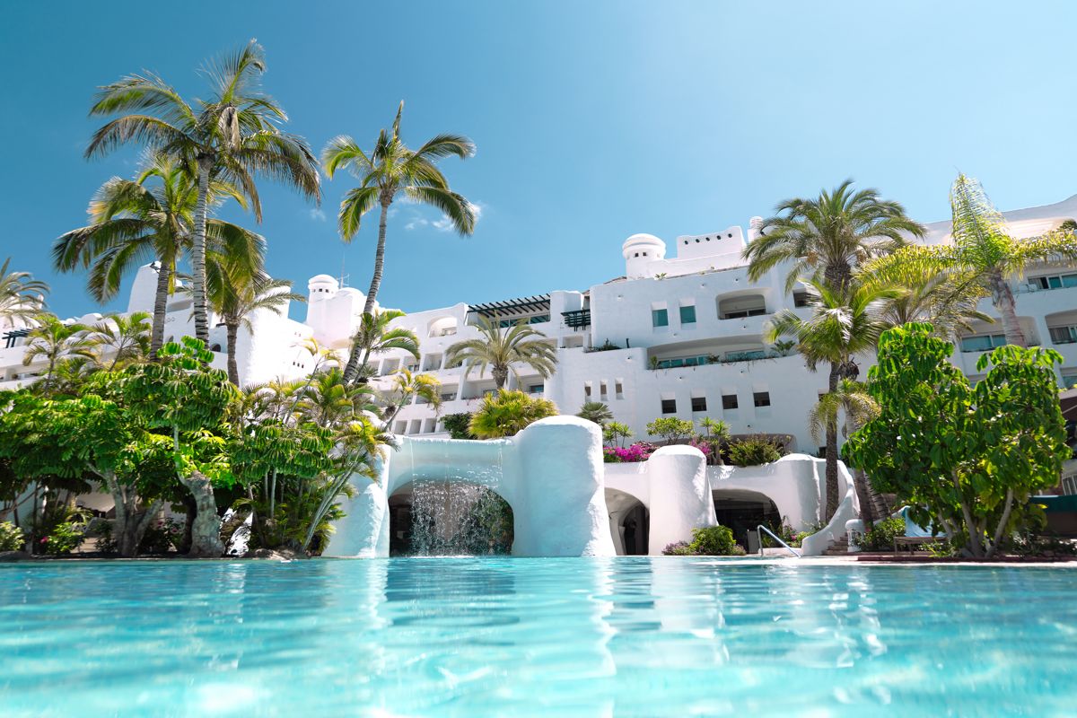 Weißes Gebäude mit Palmen und Pool in Costa Adeje, Tenerife.