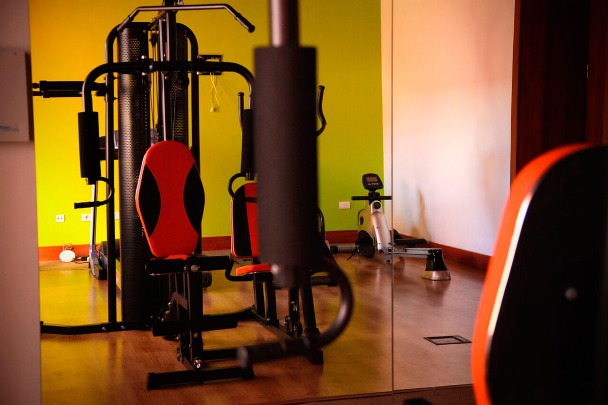 Fitnessstudio in Teneriffa mit roten Geräten und grünem Hintergrund.