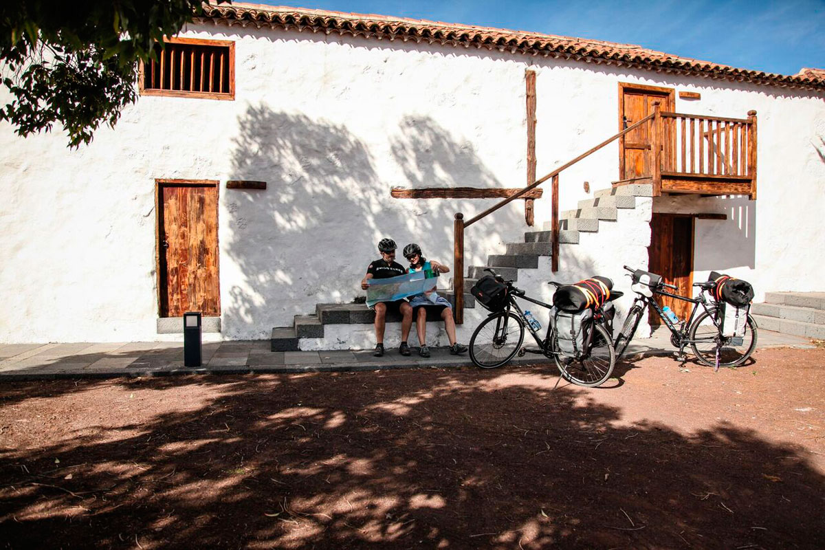 Zwei Personen mit Karte sitzen vor einem weißen Gebäude in La Orotava, Teneriffa.