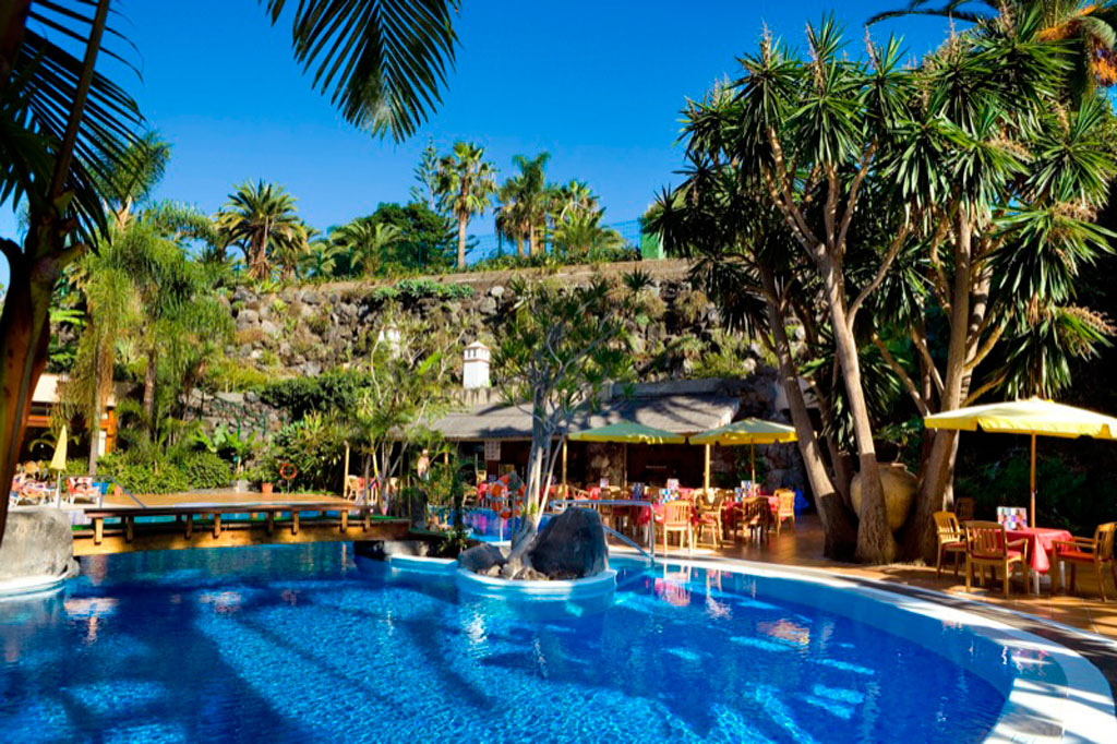 Poolbereich mit Palmen und Restaurant in einem Hotel auf Teneriffa.