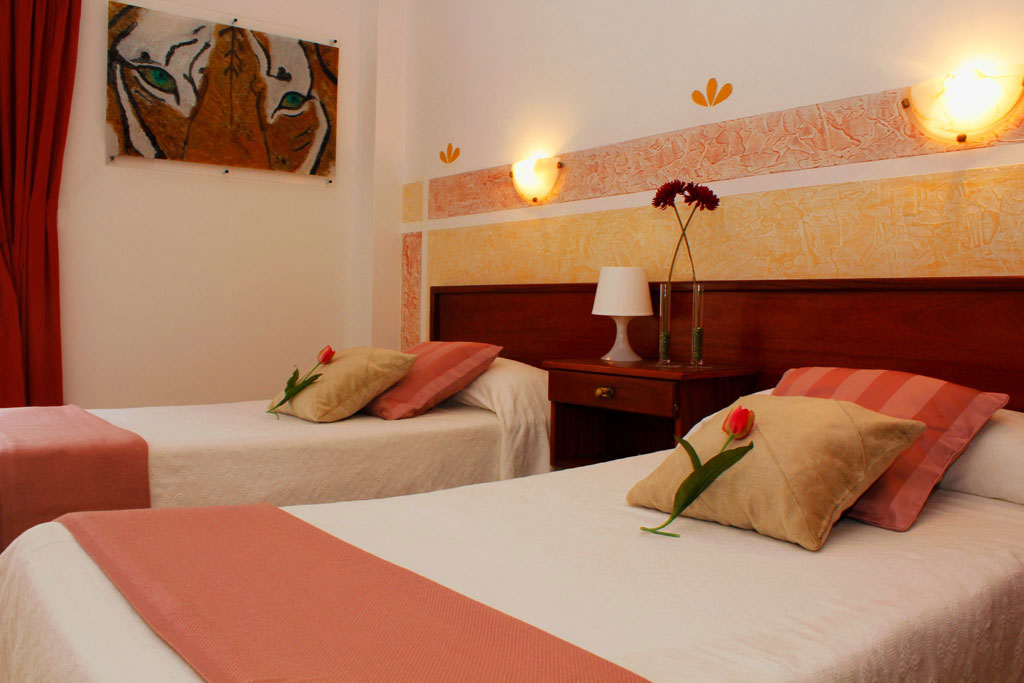 Zwei Einzelbetten mit rosa Kissen in einem Zimmer in Puerto de la Cruz, Teneriffa.