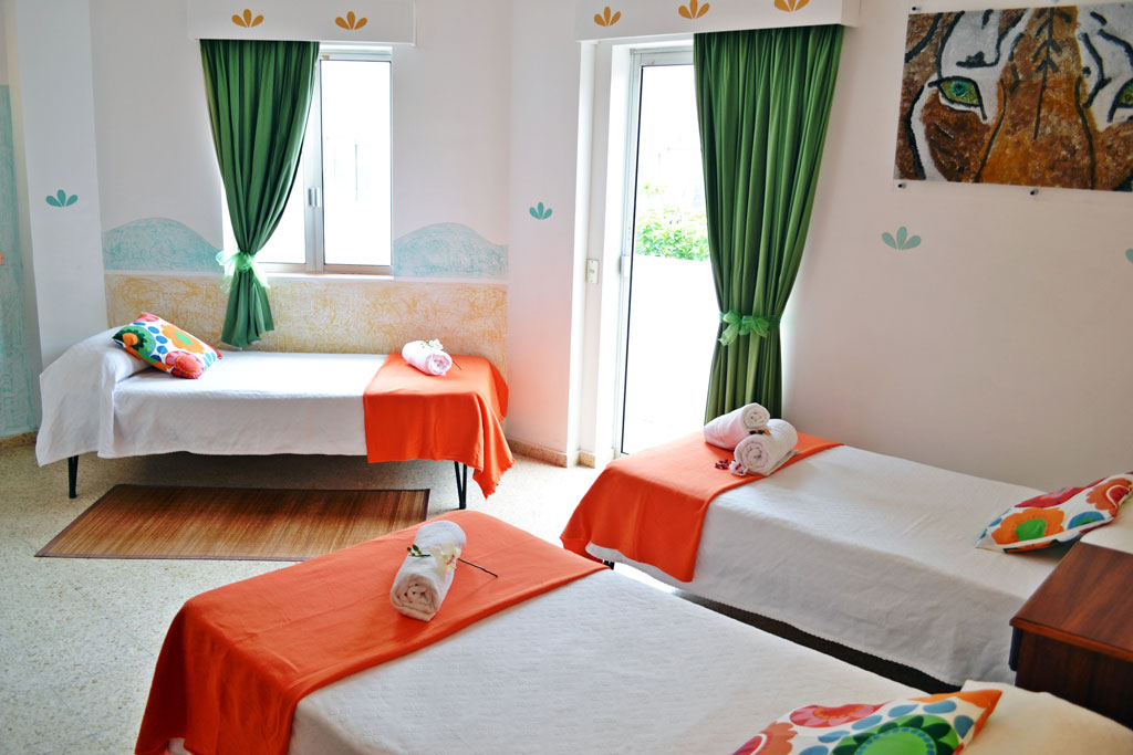 Drei Betten mit farbigen Kissen in einem Zimmer in Puerto de la Cruz, Tenerife.