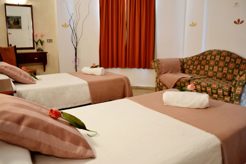 Zwei Betten mit Blumen und Handtüchern im Hotelzimmer in Tenerife.