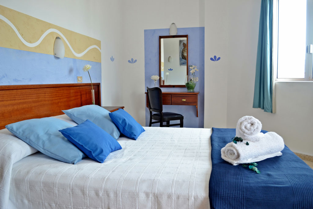 Geräumiges Schlafzimmer mit blau-weißer Bettdecke in Hotelzimmer in Teneriffa.