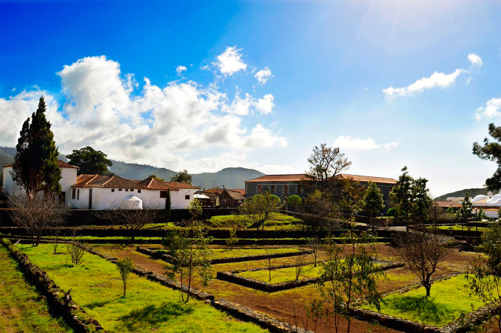 Historische Gebäude und Gartenlandschaft in Vilaflor, Teneriffa unter blauem Himmel.