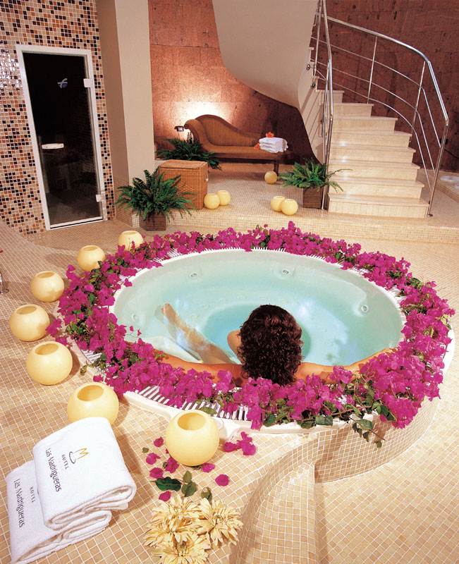 Person entspannt im Whirlpool mit Blumen und Kerzen, Spa-Bereich, Les Meridiennes.