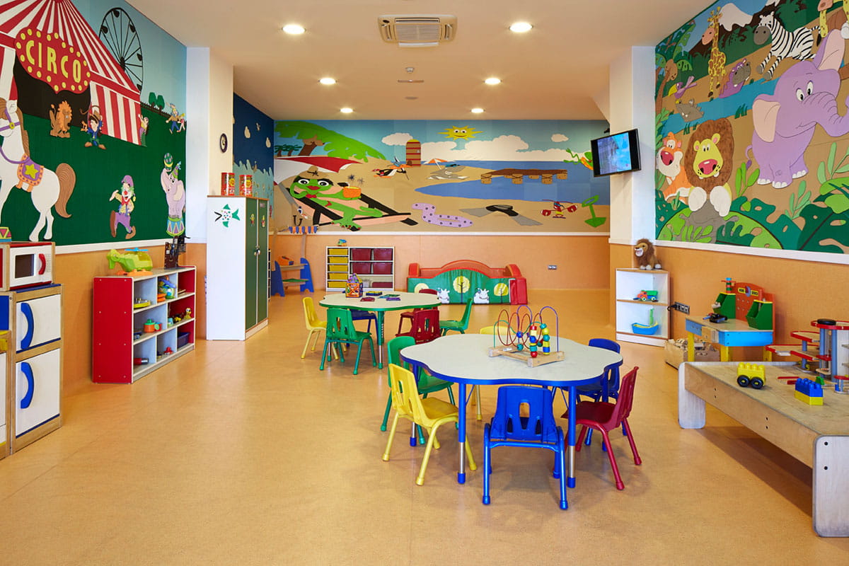Bunte Kinderspielzimmer in Puerto de la Cruz mit Tischen und Wandgemälden.