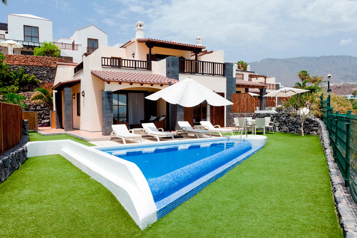Villa mit Pool und Liegestühlen auf grünem Rasen in Arona, Teneriffa.