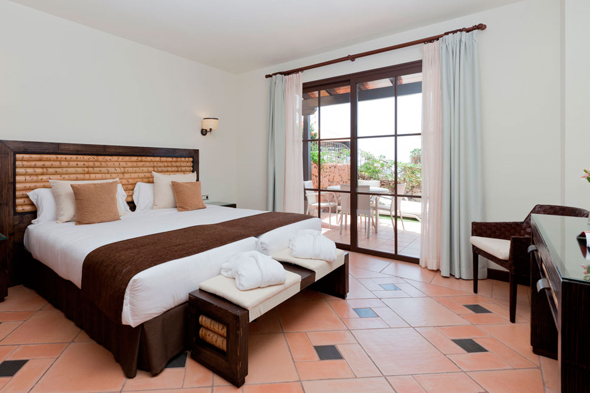 Hell zu Zimmer mit Bett, Glas-Schiebetür mit Blick auf Garten in Teneriffa.