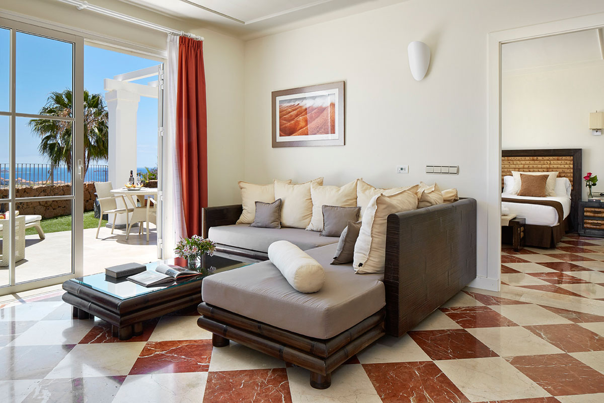 Wohnzimmer mit Meerblick und Balkon, Sofa, Tisch, offene Tür zum Schlafzimmer in Teneriffa.