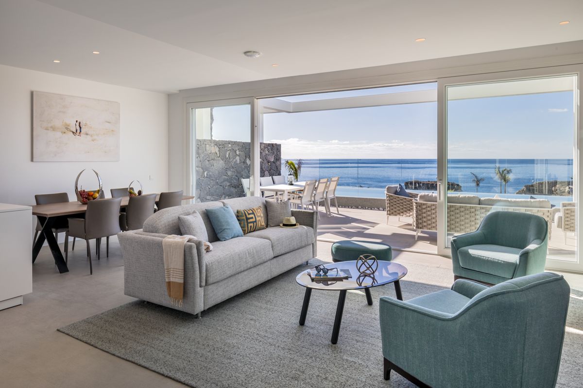 Wohnzimmer mit Meerblick in Tenerife, Sofa und Sessel, Glastisch, Essbereich.