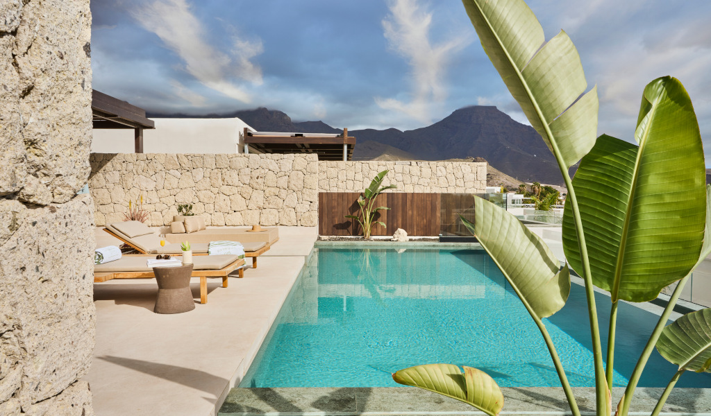 Sonnenliegen und Pool mit Pflanzen im Hintergrund in Adeje, Teneriffa.