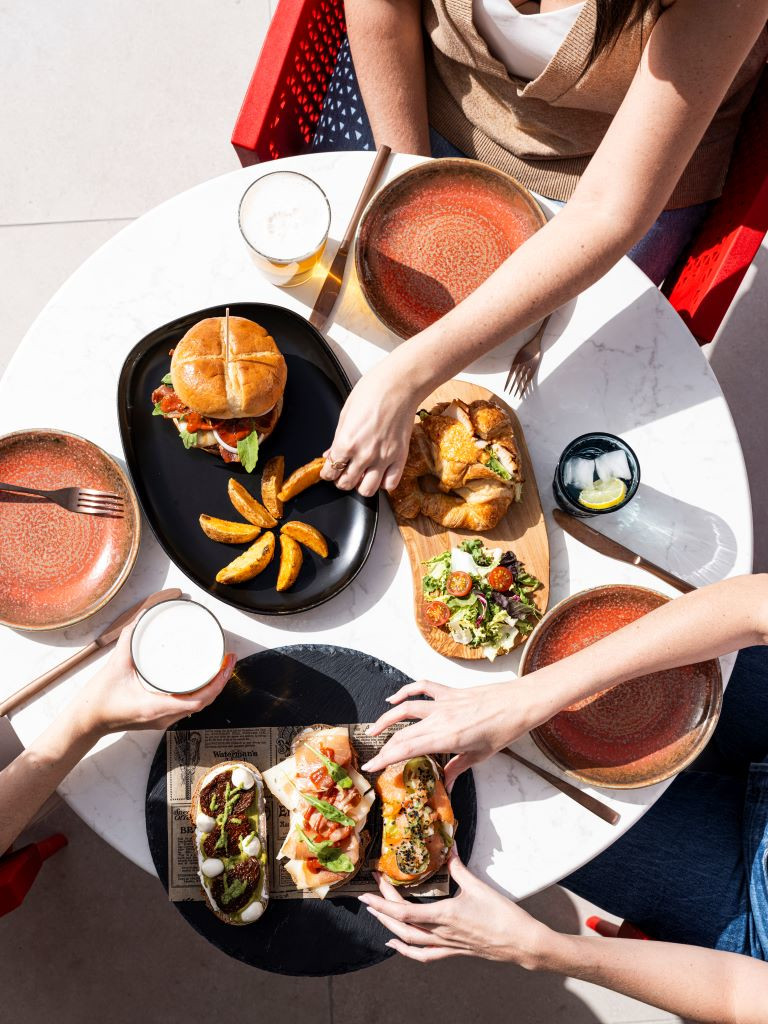 Tisch mit Hamburger, Pommes, Salat und Getränken in einem Restaurant auf Teneriffa.