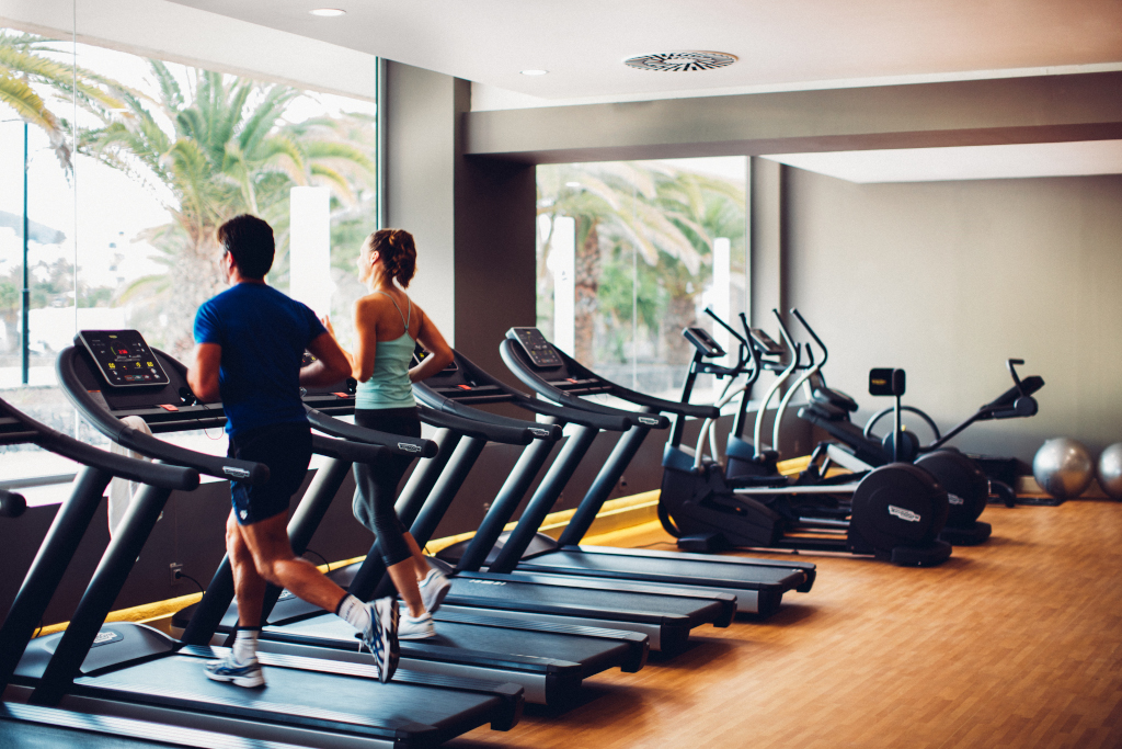 Mann und Frau trainieren auf Laufbändern in einem Fitnessstudio in Tenerife.