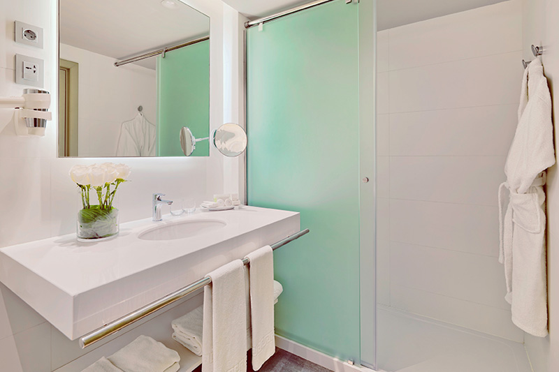 Modernes Badezimmer mit Blumen auf dem Waschbecken und Handtüchern im Los Cristianos Hotel.