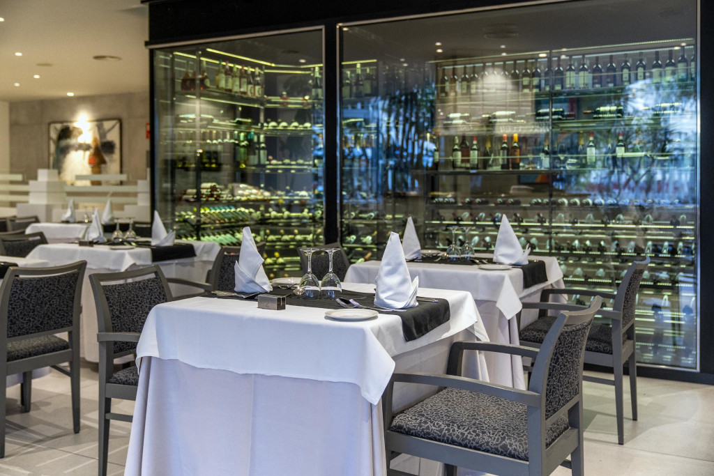 Elegantes Restauranttische mit gefalteten Servietten vor einer Weinvitrine in Tenerife.