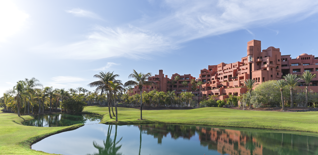 Rotes Gebäude und Palmen vor einem kleinen See in Costa Adeje.