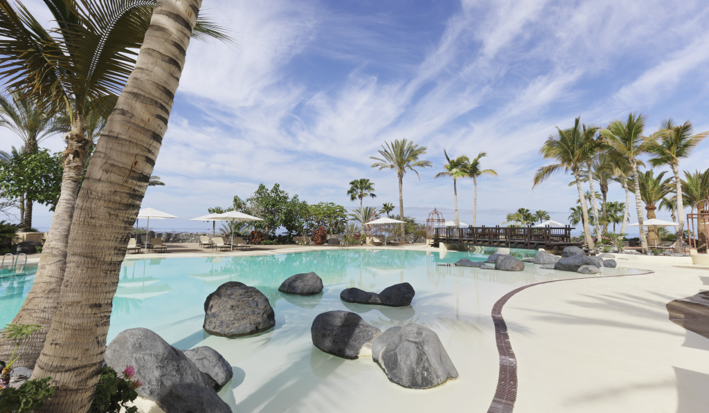 Pool mit Palmen und Felsen in einem Hotel in Costa Adeje, Teneriffa.