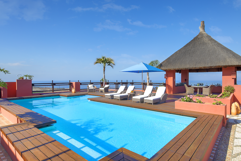 Pool mit Liegestühlen und Pavillon, Meerblick in Teneriffa im Hintergrund.