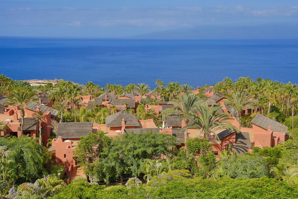 Rosa Gebäude und Palmen am Meer in Adeje, Teneriffa.