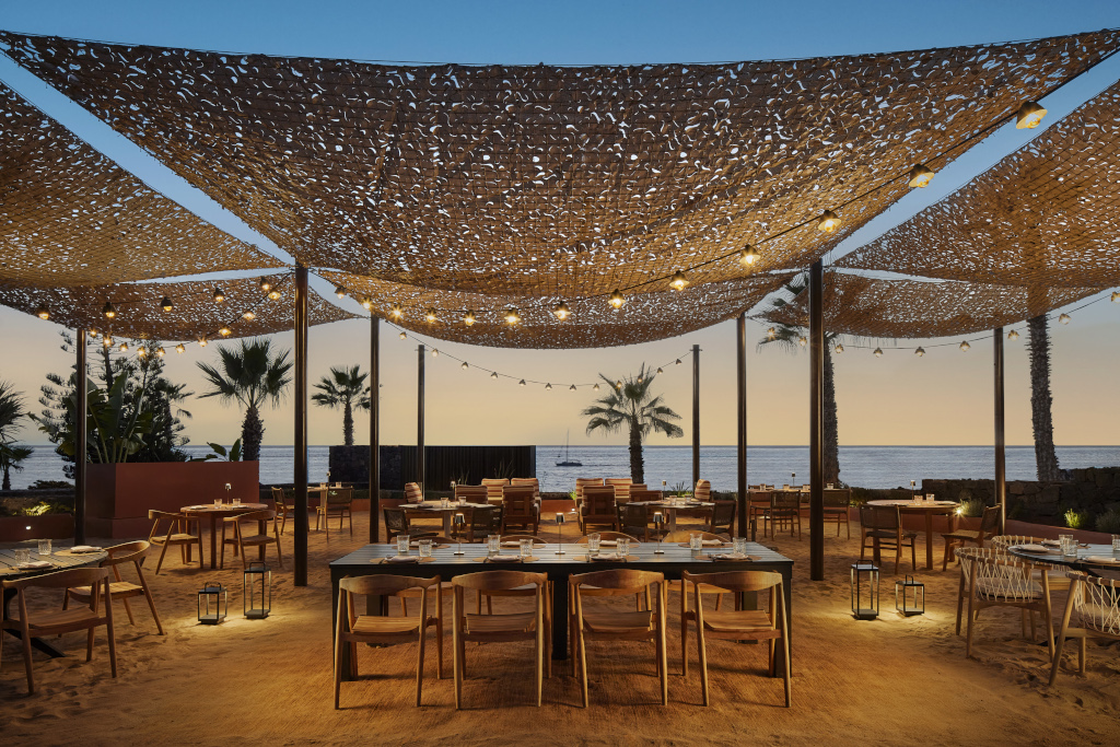 Restaurant am Strand bei Sonnenuntergang in Costa Adeje, mit beleuchteter Terrasse.