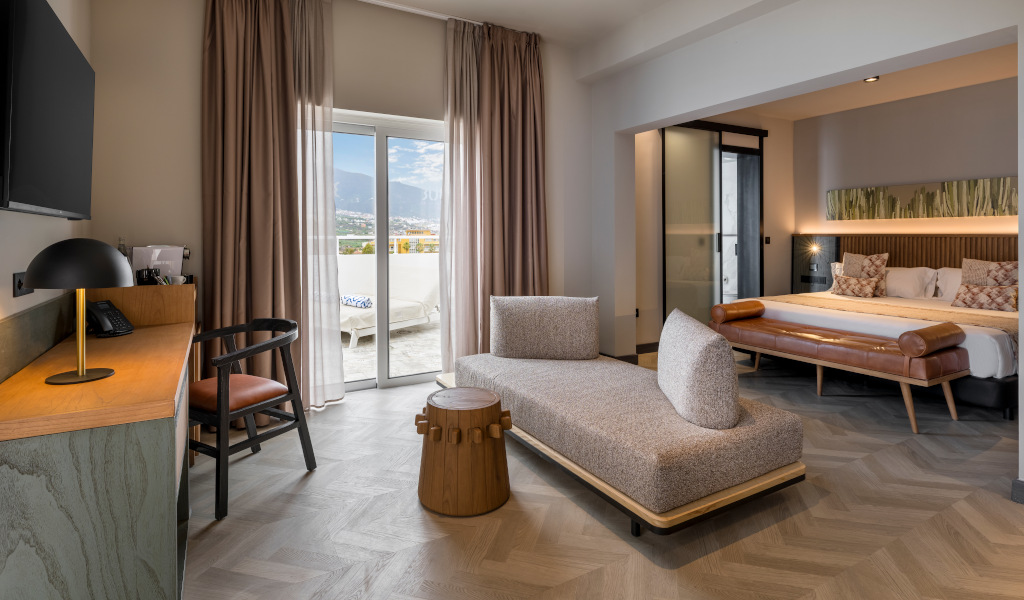 Modernes Hotelzimmer mit Sofa, Bett und Blick auf Puerto de la Cruz in Teneriffa.