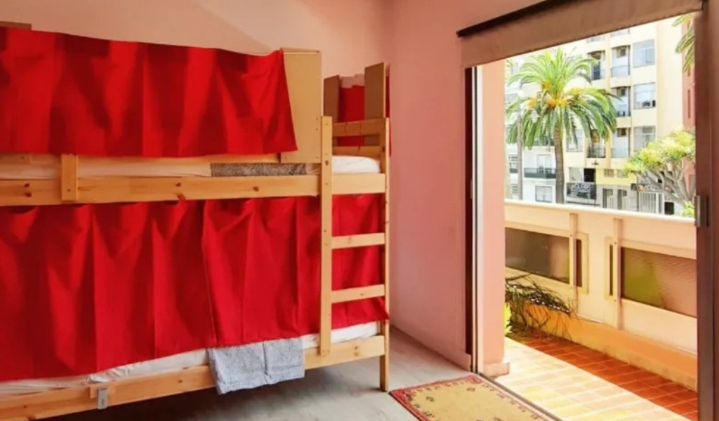 Etagenbett mit roten Vorhängen in einem Raum mit Balkon in Santa Cruz de Tenerife.