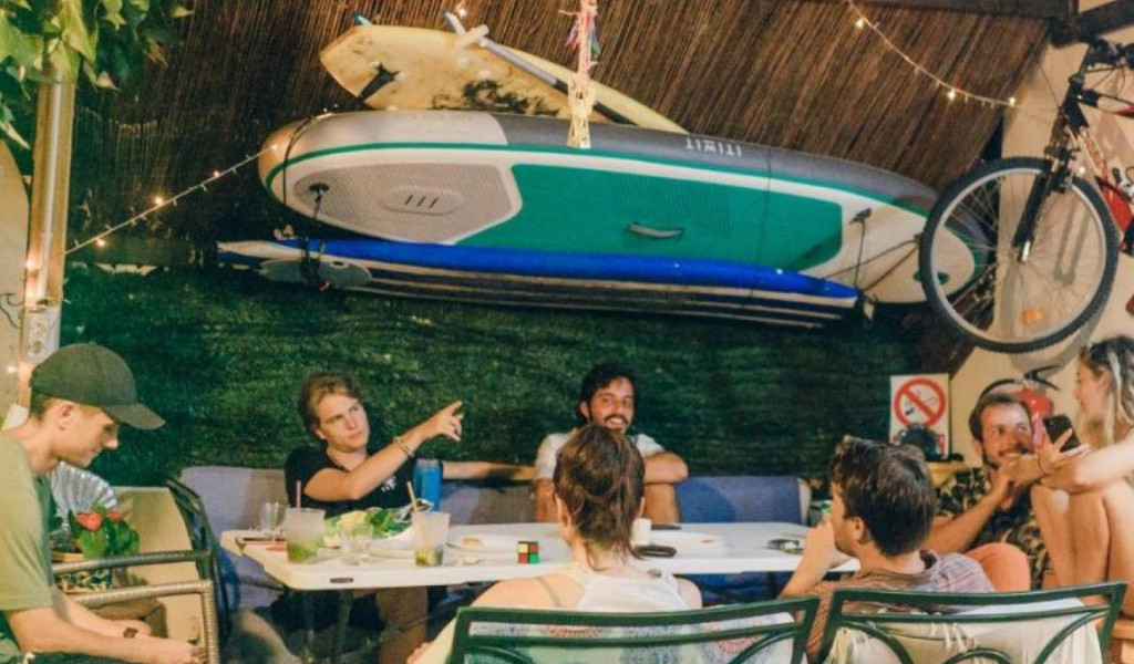 Personengruppe bei einem Tisch im Freien mit Surfbrett und Fahrrad in einer Bar in Tenerife.