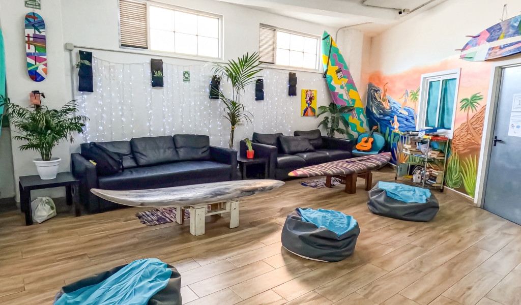 Gemütlicher Gemeinschaftsraum in Teneriffa mit Sofas, Surfbrettern und Pflanzen.