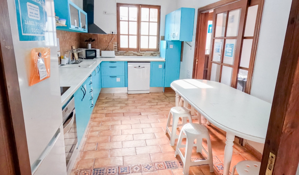 Küche mit blauem Schrank, Tisch und Hockern in einer Unterkunft in Tenerife.