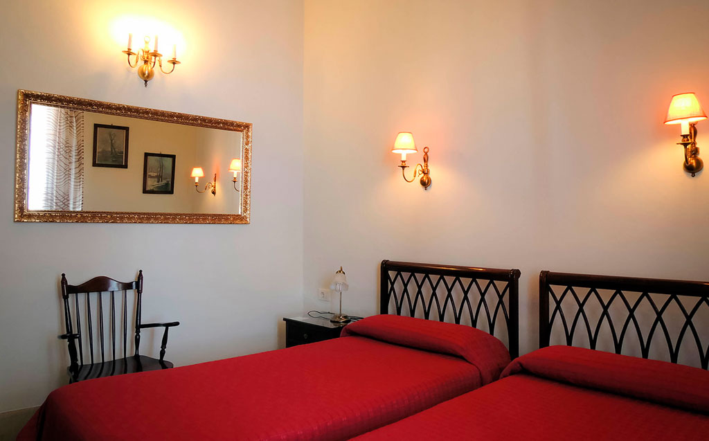 Zwei Einzelbetten mit roten Bettdecken im Hotelzimmer in Teneriffa.
