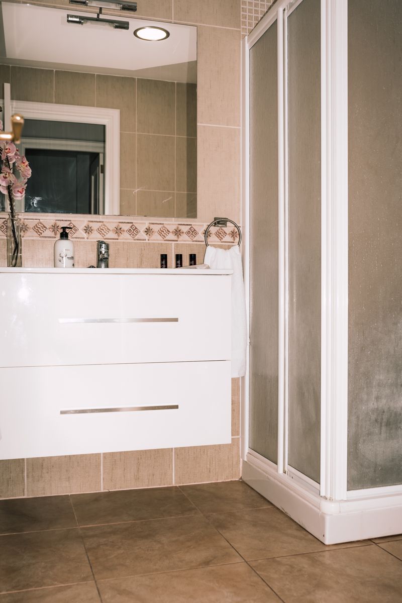 Weißes Badezimmer mit Duschkabine und Spiegel in einem Hotel in Tenerife.