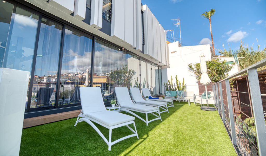 Sonnenliegen und Glasfenster auf Terrasse mit Blick in Santa Cruz de Tenerife.